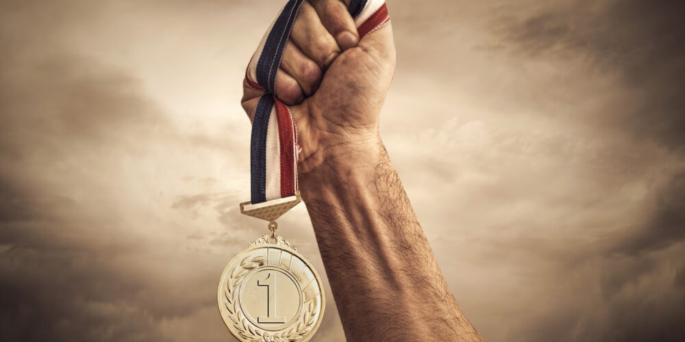 Zum Himmel gestreckter Arm mit Sieger-Medaille in der Hand