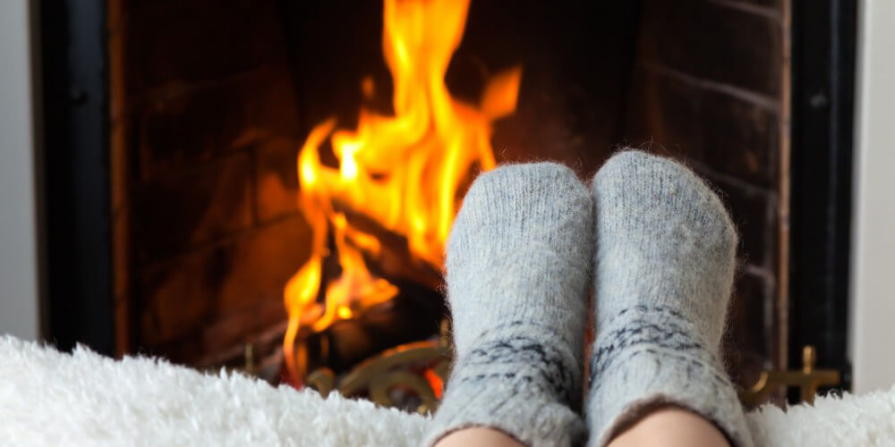 Füße eines Kindes mit warmen Socken, im Hintergrund Kaminfeuer
