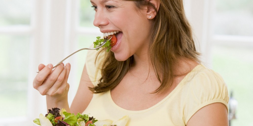 Schwangere, lchelnde Frau isst frischen Salat