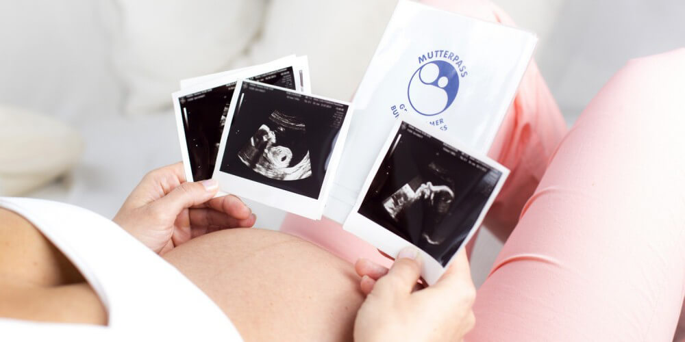 Schwangere Frau mit Mutterpass und Ultraschallbildern