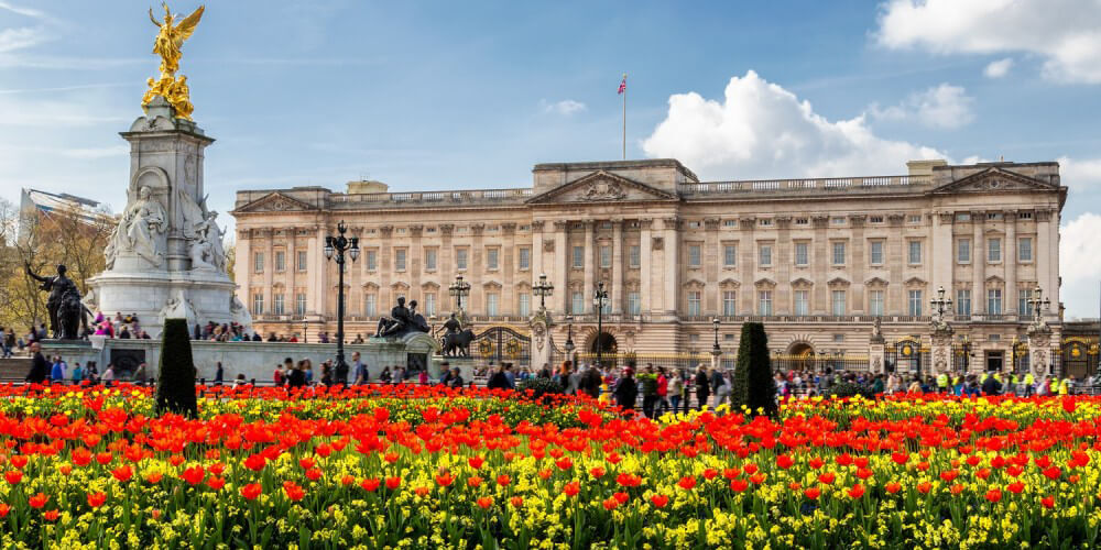 Buckingham Palace in London hinter leuchtend rot-gelben Blumenbeeten