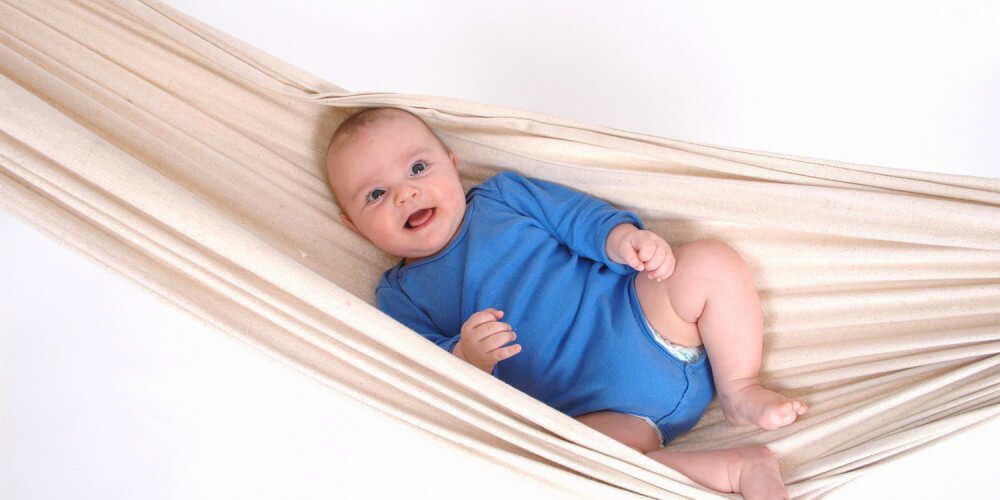 Baby in blauem Body liegt in einer Hngematte