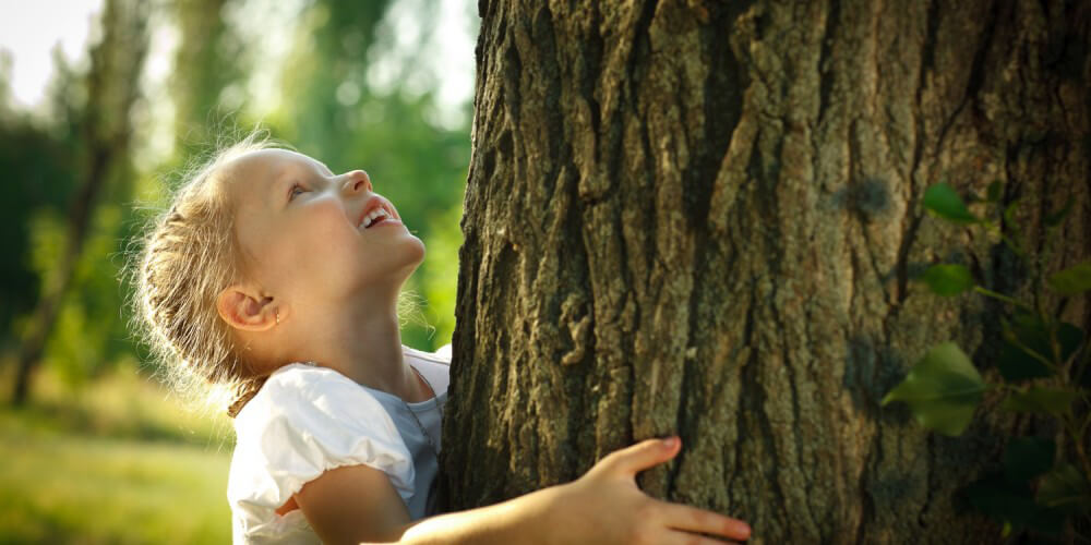 Kleines Mädchen umarmt einen Baum