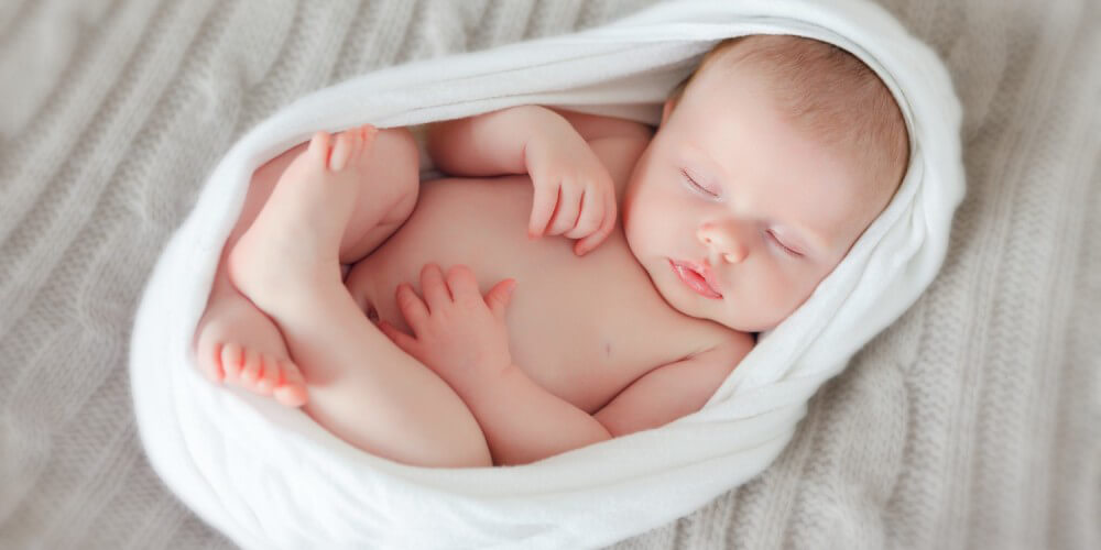 Schlafendes Baby in weißem Tuch