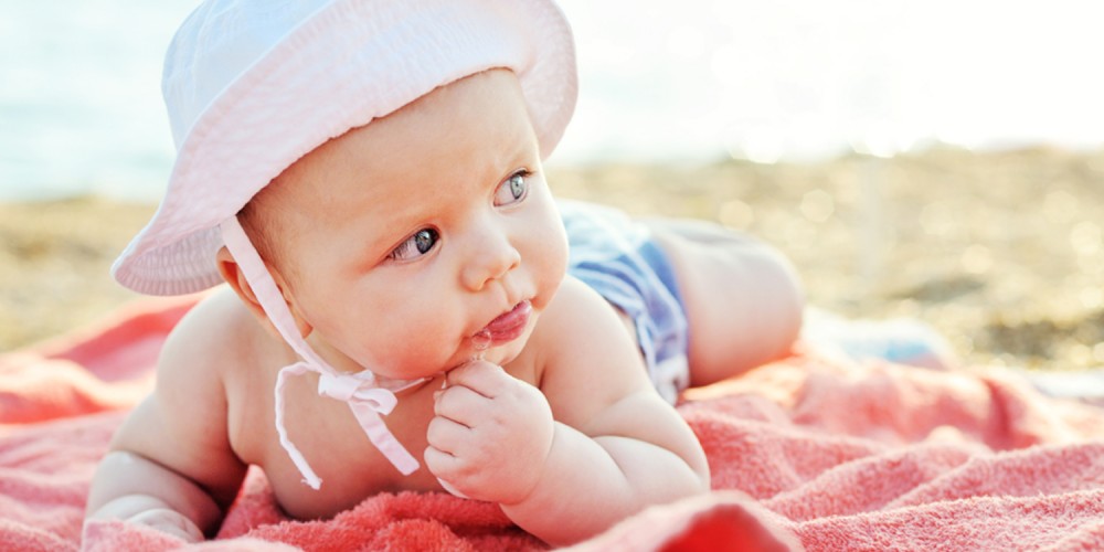 Baby mit Sonnenhut am Strand