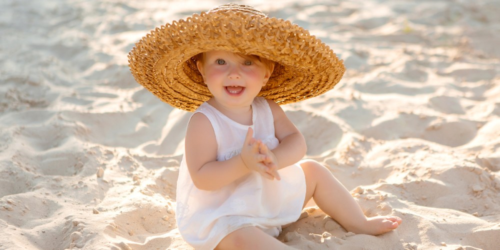 Kleines Mädchen mit Strohhut im Sand