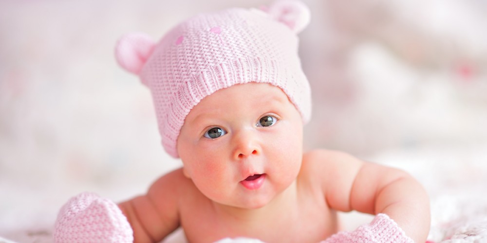 Neugeborenes mit rosafarbener Mtze und Fustlingen