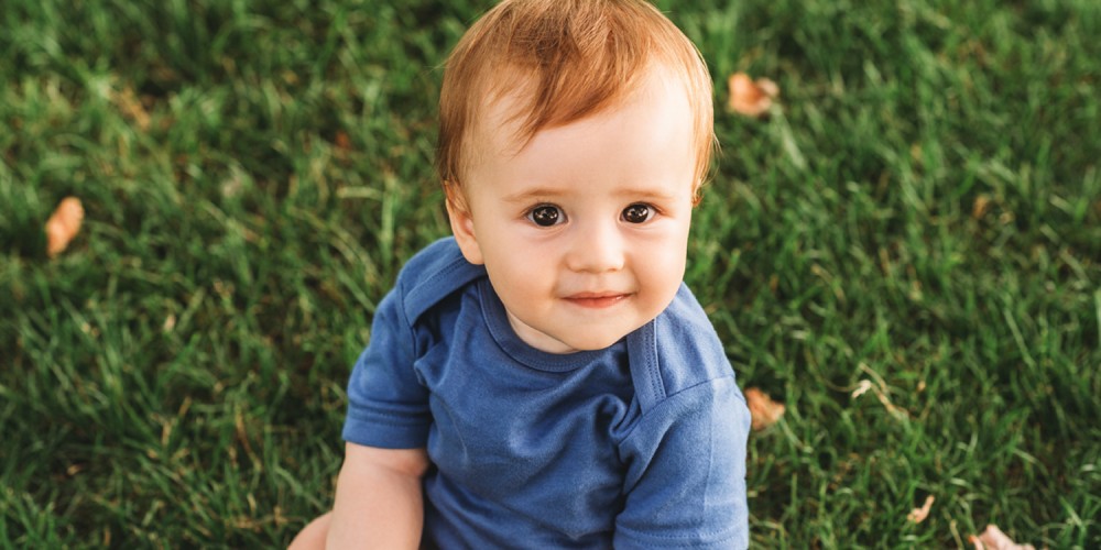 Kleiner Junge sitzt auf grnem Rasen