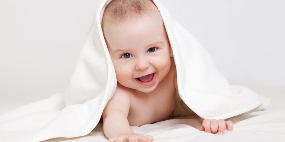 Lchelndes Baby unter weiem Handtuch