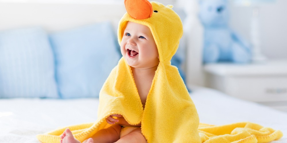 Lachendes Baby in gelbem Enten-Handtuch
