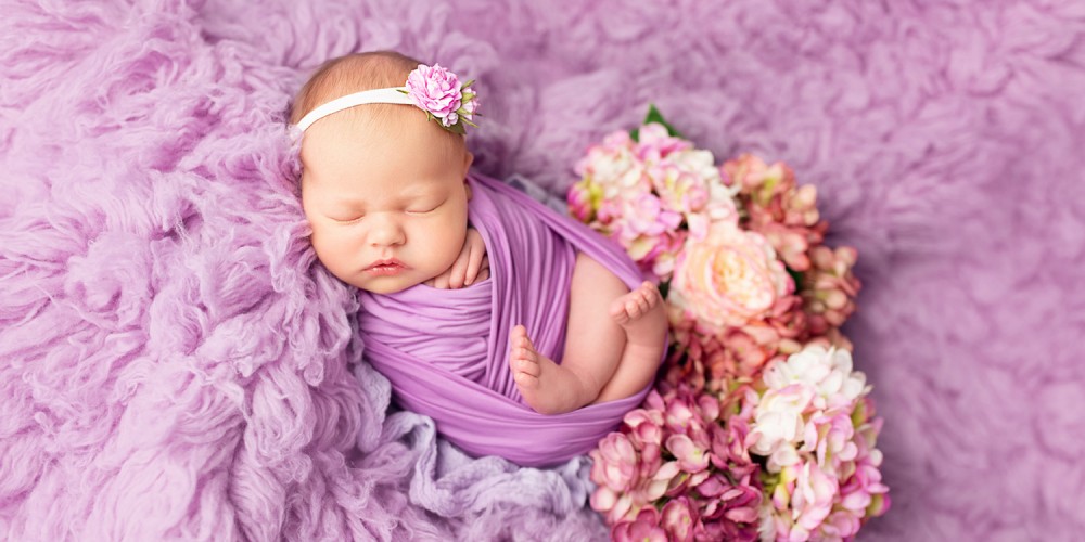 Schlafender Säugling in lila Decke gepuckt