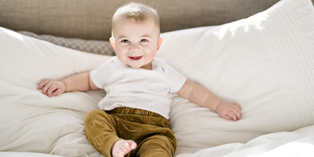 Lchelndes Baby sitzt in einem Bett