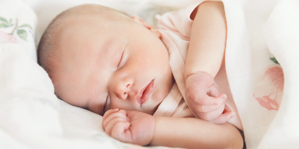 Schlafendes Baby unter Blumendecke