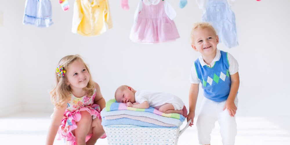 Zwei Kleinkinder neben einem Neugeborenen
