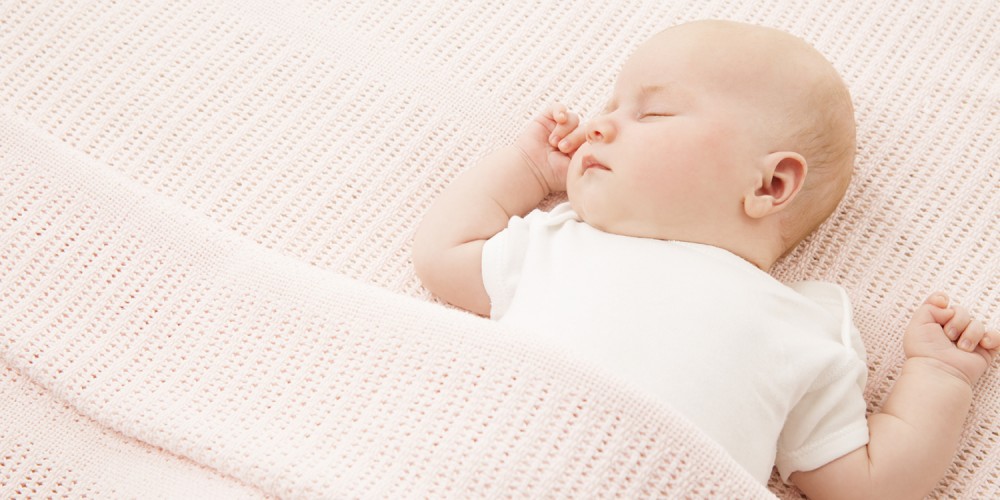 Schlafender Sugling unter rosa Decke