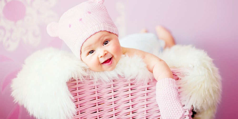 Baby mit rosa Mtze liegt in einem pinken Korb