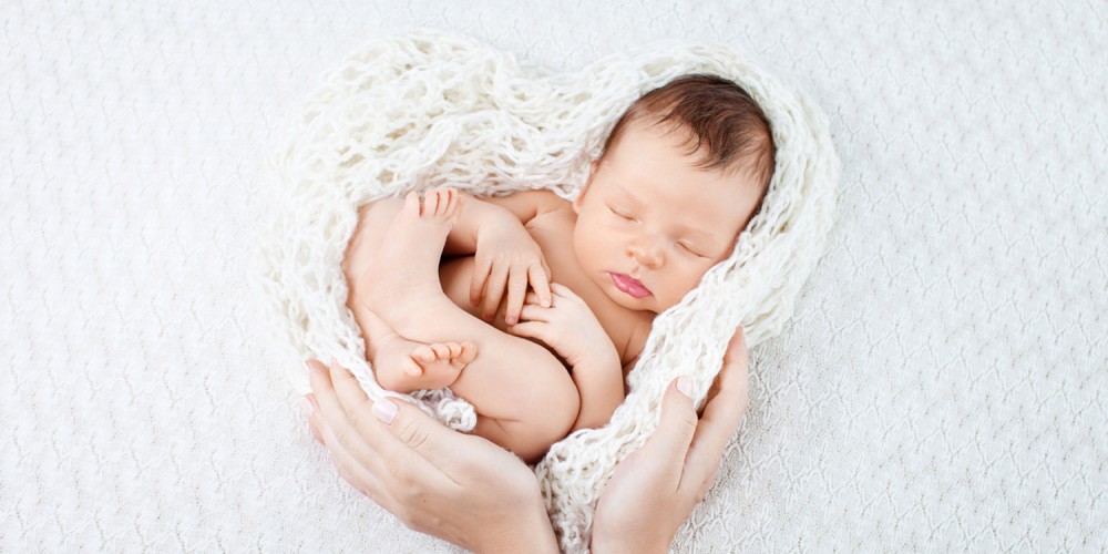 Schlafender Säugling in den Händen seiner Mutter