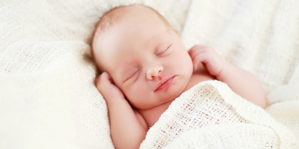 Schlafendes Neugeborenes unter weißer Decke