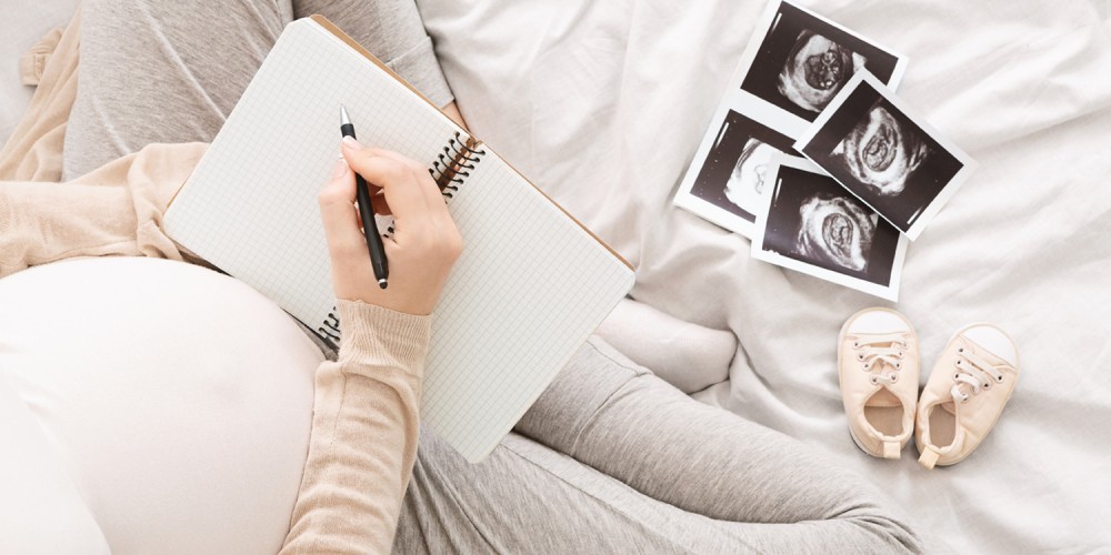 Schwangere Frau notiert Vornamen auf einem Notizblock