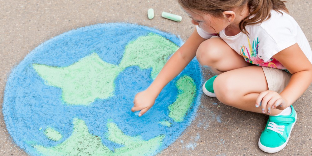 Mädchen malt Weltkugel mit Kreide