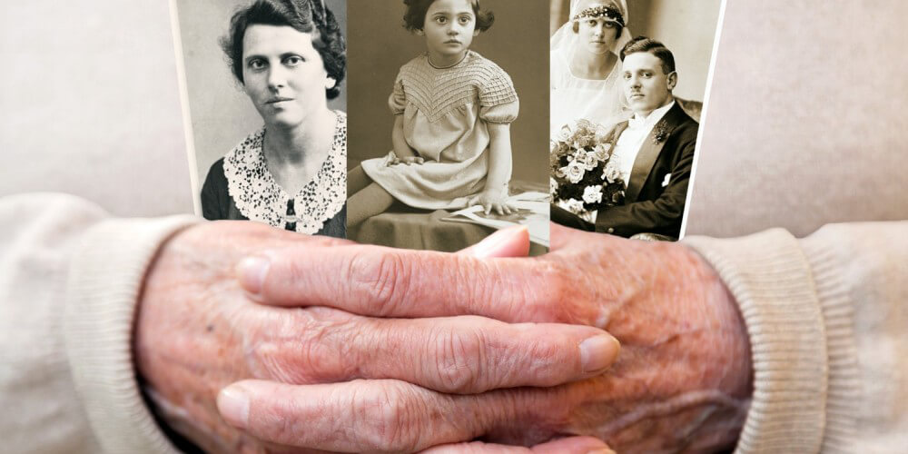 Gefaltete Seniorenhände halten drei alte schwarz-weiße Familienfotos