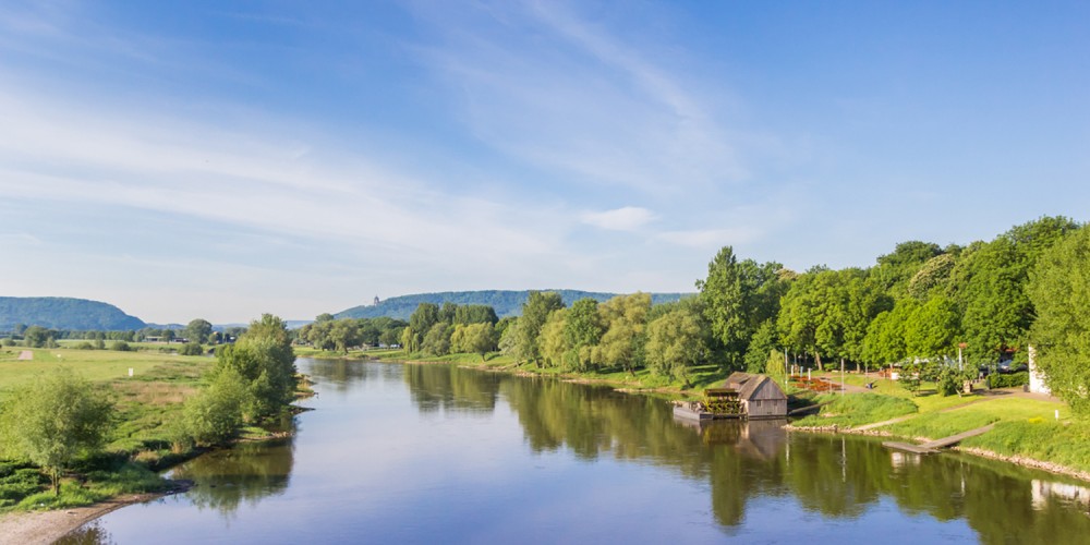 Blick ber den Fluss Weser unter blauem Himmel, alte Mhle am Ufer