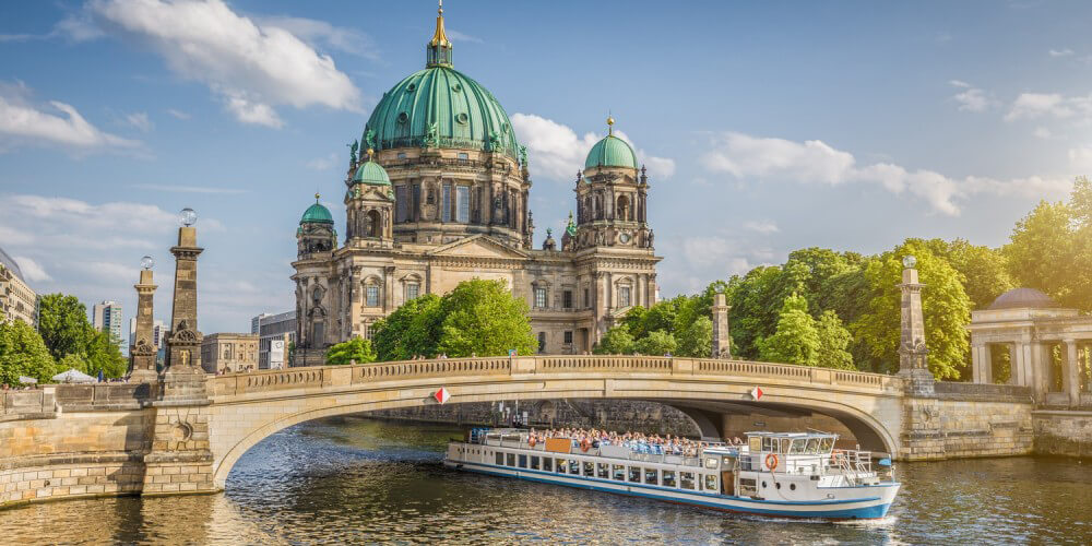 Ein Sightseeing-Schiff fhrt unter einer Brcke der Spree hindurch, im Hintergrund der Berliner Dom