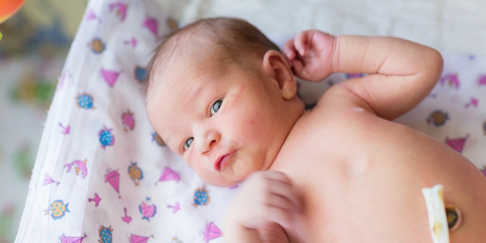 Neugeborenes mit abgeklebtem Nabel auf einer Wickelunterlage