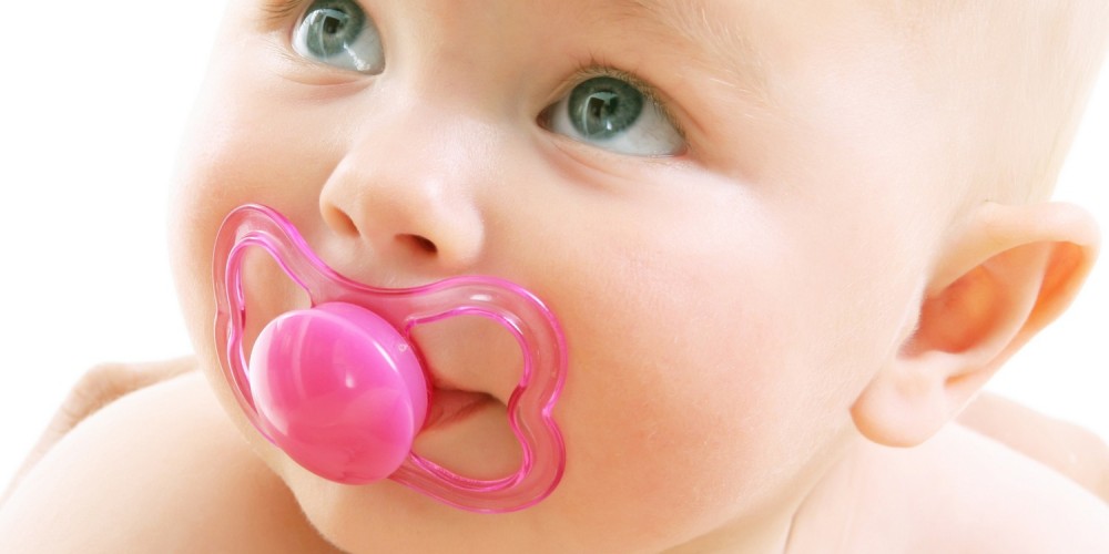 Baby mit pinkem Schnuller im Mund