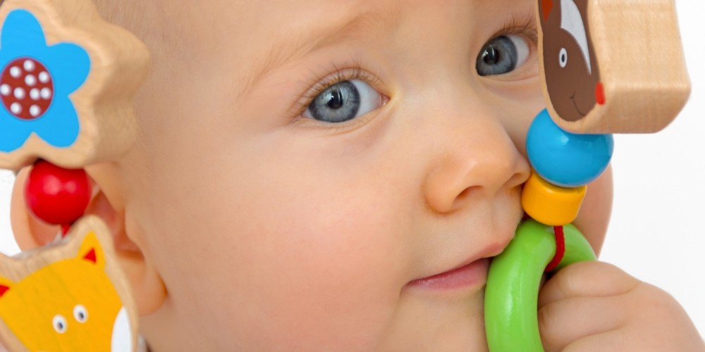 Baby spielt mit einer bunten Holzspielzeugkette