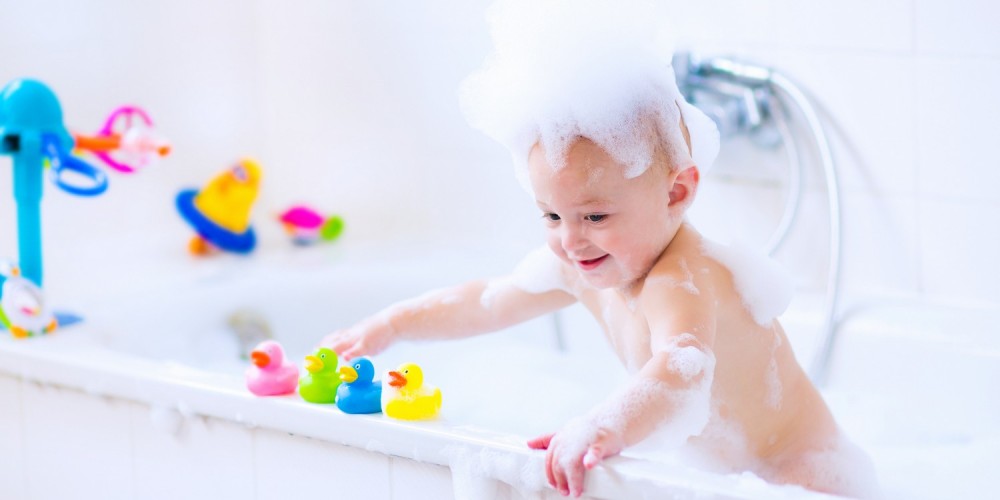 Kleinkind mit Wasserspielzeug in der Badewanne