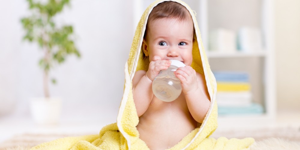 Baby in gelbem Handtuch und mit Fläschchen Baby in gelbem Handtuch und mit Fläschchen