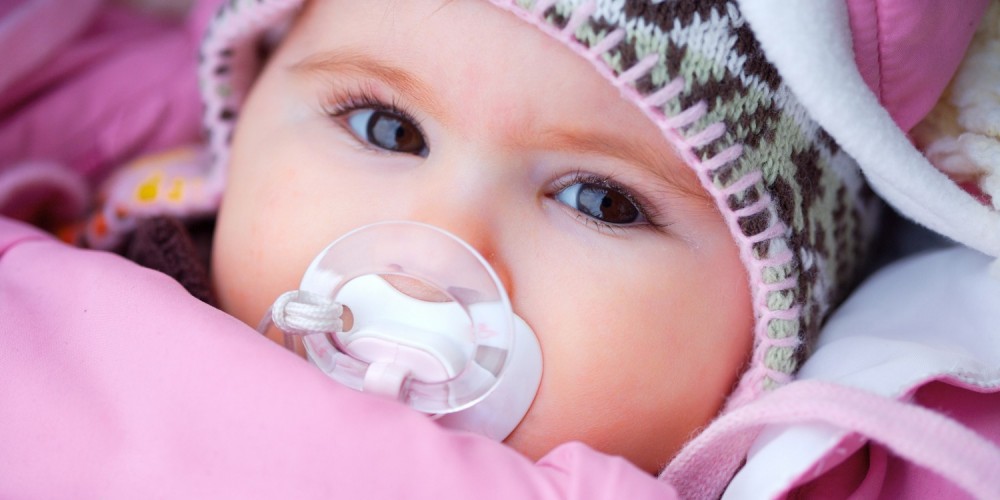 Baby mit Schnuller und Mtze