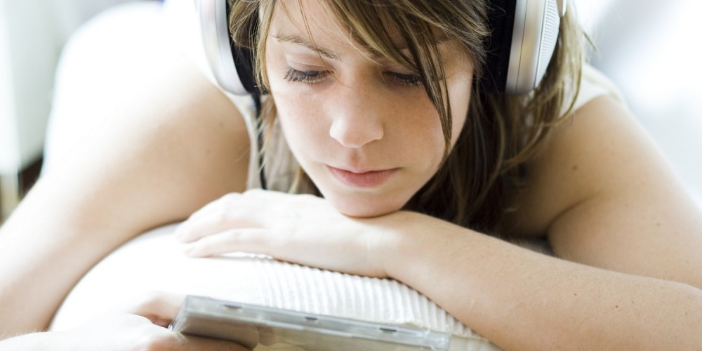 Junge Frau mit Kopfhörern hört eine CD