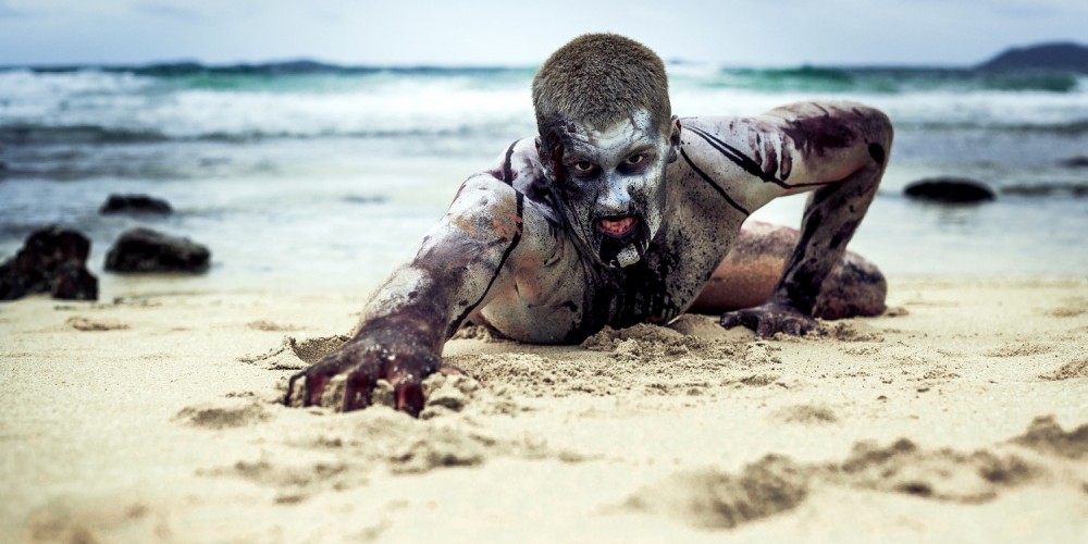 Zombie kriecht über einen Strand